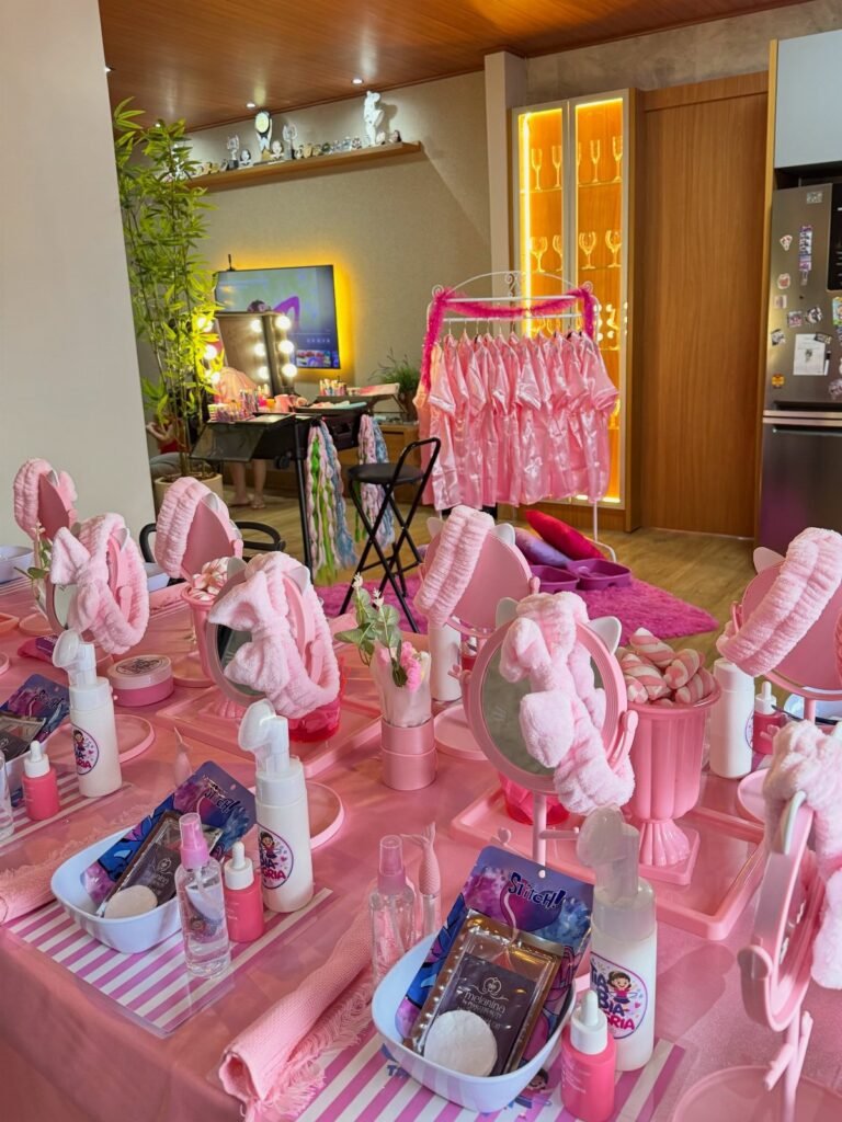 Pink spa party setup with skincare products, headbands, and robes on a table.