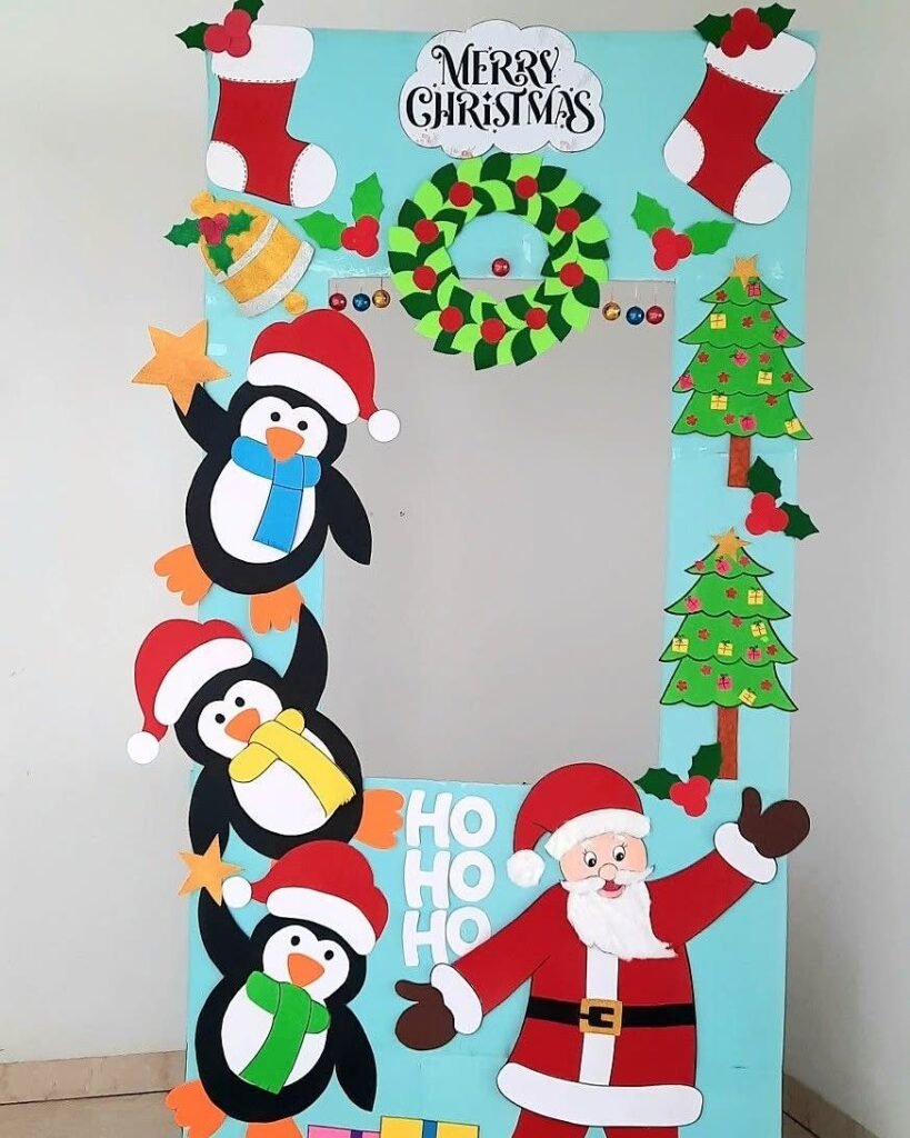 A large blue Christmas-themed photo booth frame decorated with penguins, Santa, and festive holiday ornaments.